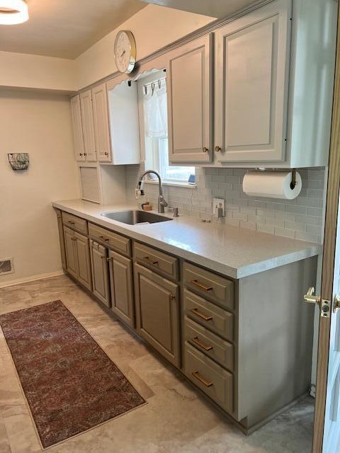 kitchen with light countertops, baseboards, a sink, and tasteful backsplash