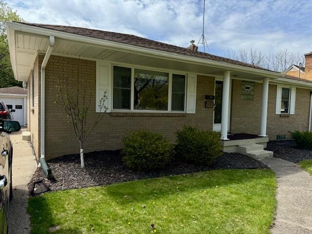single story home with brick siding, a chimney, and a front yard
