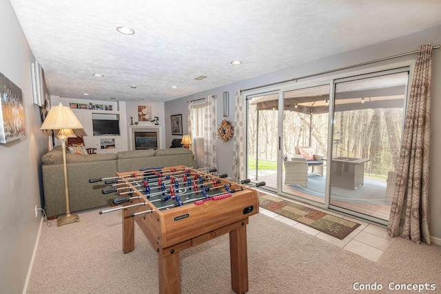 playroom featuring recessed lighting, a textured ceiling, a glass covered fireplace, and baseboards