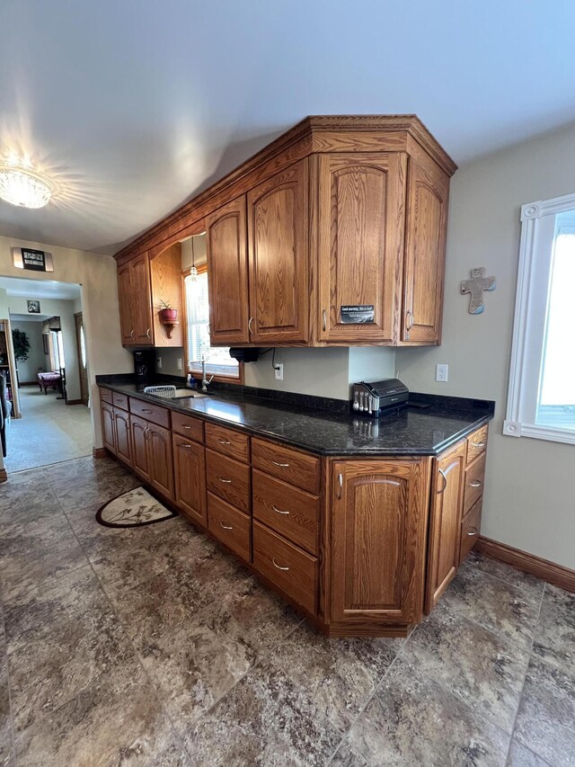 3817 Butterworth St SW, Grand Rapids, MI 49534 - kitchen with a sink, dark countertops, baseboards, and brown cabinets