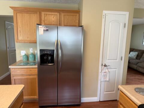 935 E 6th St, Pentwater, MI 49449 - kitchen with light countertops, baseboards, stainless steel refrigerator with ice dispenser, and dark wood-style floors