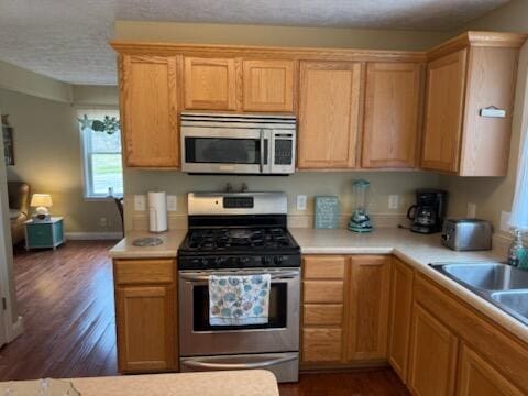935 E 6th St, Pentwater, MI 49449 - kitchen featuring baseboards, dark wood-style floors, light countertops, a textured ceiling, and appliances with stainless steel finishes