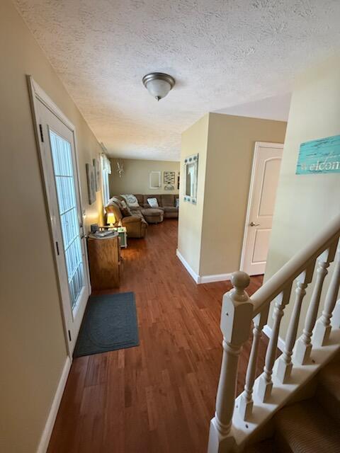 935 E 6th St, Pentwater, MI 49449 - hall featuring a textured ceiling, baseboards, wood finished floors, and stairway