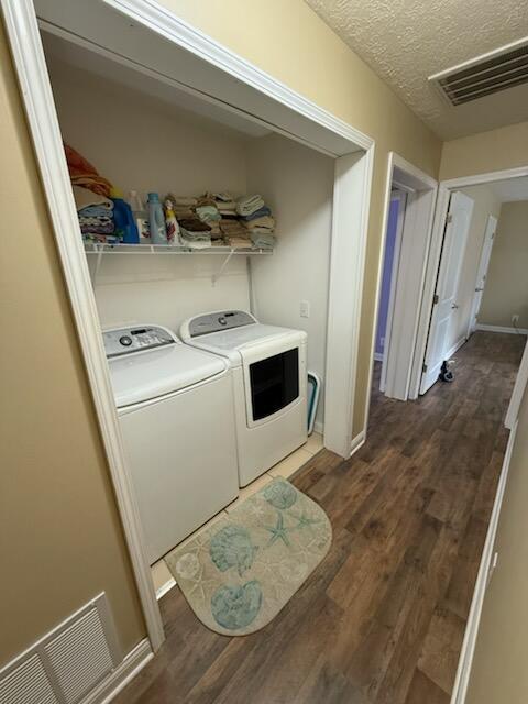 935 E 6th St, Pentwater, MI 49449 - laundry room with laundry area, separate washer and dryer, a textured ceiling, wood finished floors, and visible vents