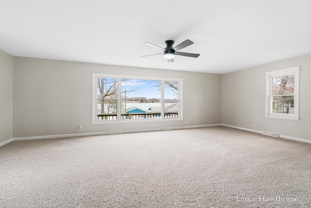 carpeted empty room featuring baseboards, visible vents, ceiling fan, and plenty of natural light