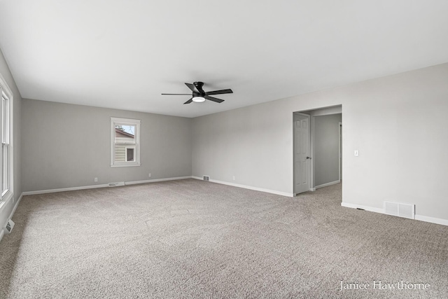 spare room with carpet, visible vents, a ceiling fan, and baseboards