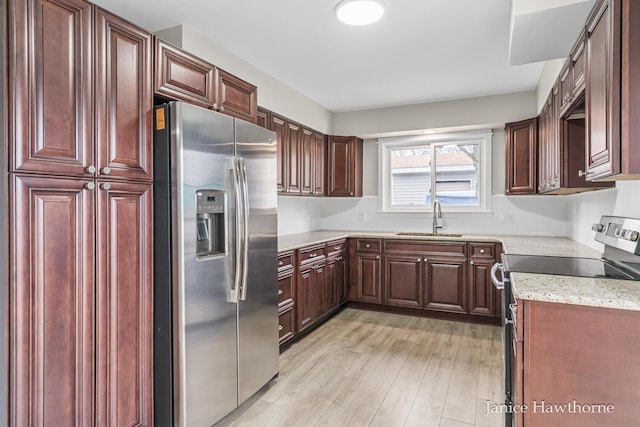 kitchen with light stone counters, a sink, light wood-style floors, stainless steel appliances, and dark brown cabinets