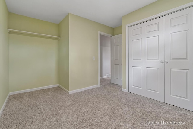 unfurnished bedroom featuring baseboards, carpet flooring, and a closet
