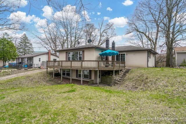 rear view of property with a deck, a yard, stairs, and a chimney
