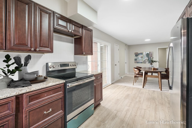 kitchen with light stone countertops, stainless steel appliances, dark brown cabinets, baseboards, and light wood-type flooring