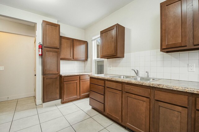 311 Robey Pl SE, Grand Rapids, MI 49506 - kitchen with a sink, brown cabinets, light tile patterned flooring, tasteful backsplash, and baseboards