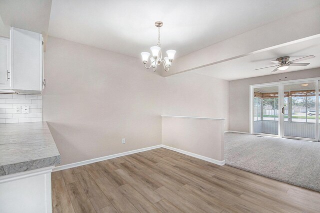 5984 Leisure S Dr SE, Grand Rapids, MI 49548 - unfurnished dining area with baseboards, light wood-style flooring, and ceiling fan with notable chandelier