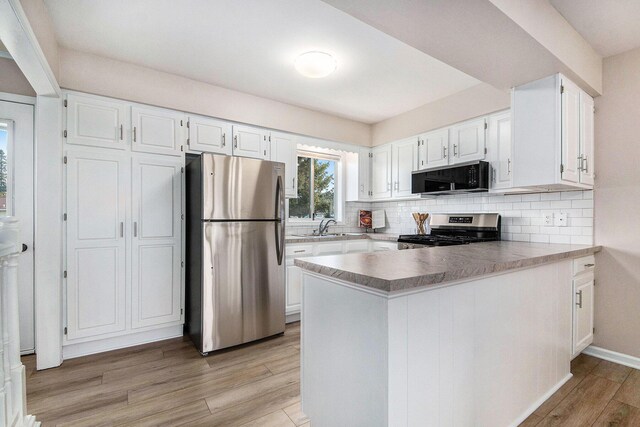 5984 Leisure S Dr SE, Grand Rapids, MI 49548 - kitchen featuring white cabinets, a sink, stainless steel appliances, a peninsula, and tasteful backsplash