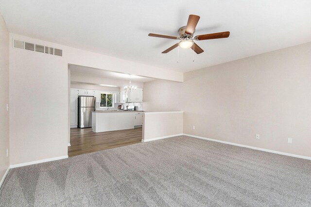 5984 Leisure S Dr SE, Grand Rapids, MI 49548 - unfurnished living room with visible vents, carpet, ceiling fan with notable chandelier, and baseboards