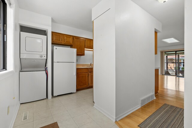 5160 Green Meadow Rd, Kalamazoo, MI 49009 - kitchen featuring brown cabinetry, visible vents, stacked washing maching and dryer, a sink, and freestanding refrigerator