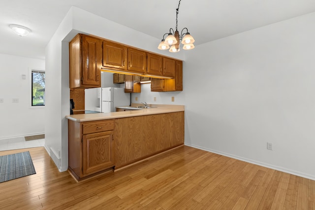 5160 Green Meadow Rd, Kalamazoo, MI 49009 - kitchen featuring brown cabinets, hanging light fixtures, an inviting chandelier, light wood-style floors, and light countertops