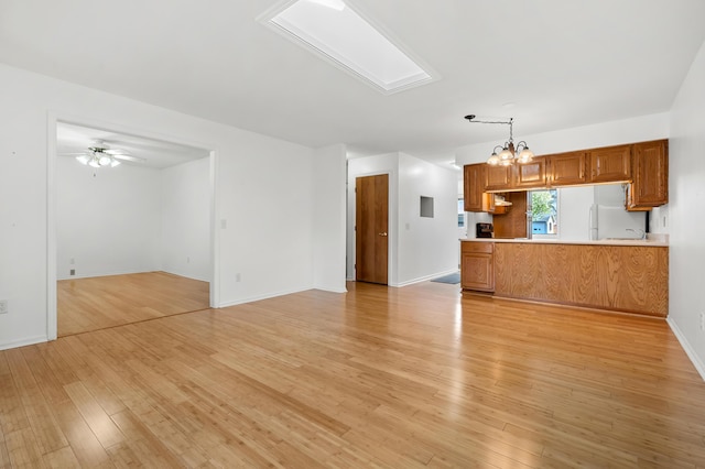 5160 Green Meadow Rd, Kalamazoo, MI 49009 - unfurnished living room featuring baseboards, ceiling fan with notable chandelier, and light wood-style flooring