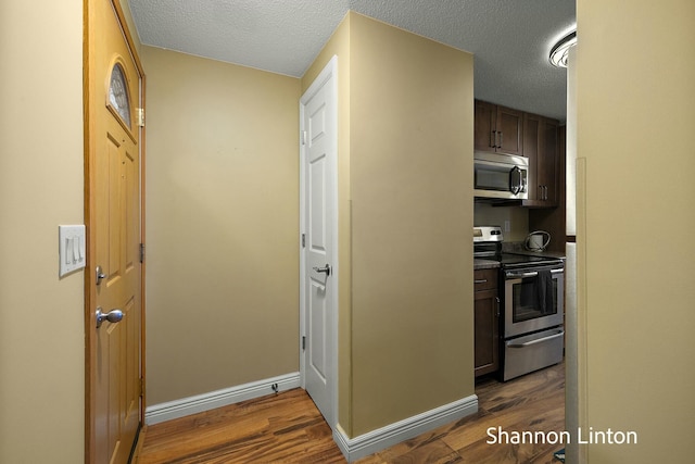 interior space with appliances with stainless steel finishes, a textured ceiling, and dark wood finished floors