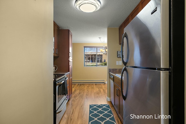 kitchen featuring a textured ceiling, brown cabinets, stainless steel appliances, a baseboard heating unit, and light wood finished floors