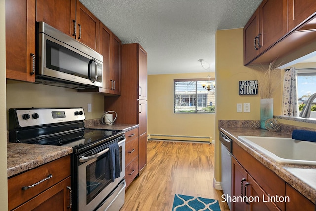 kitchen featuring a baseboard heating unit, a sink, light wood-style floors, a healthy amount of sunlight, and appliances with stainless steel finishes