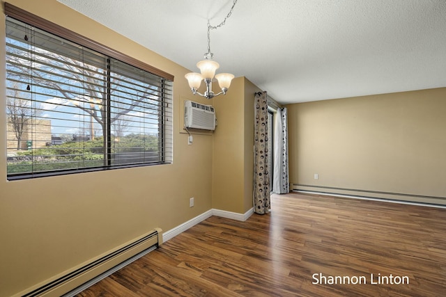 empty room featuring an inviting chandelier, a baseboard radiator, wood finished floors, and a wall unit AC