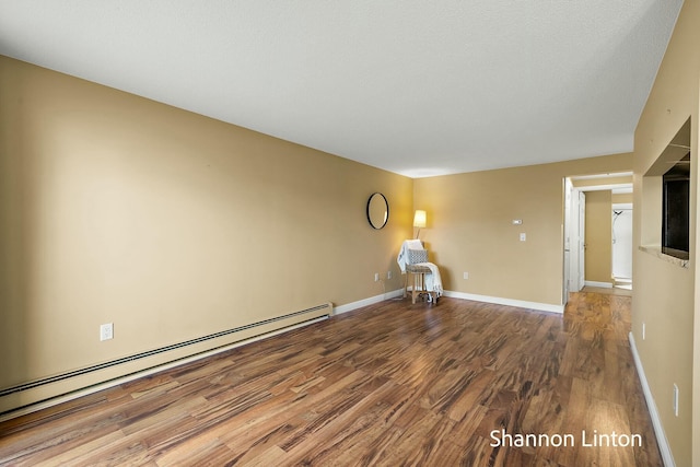 unfurnished living room featuring baseboard heating, baseboards, and wood finished floors