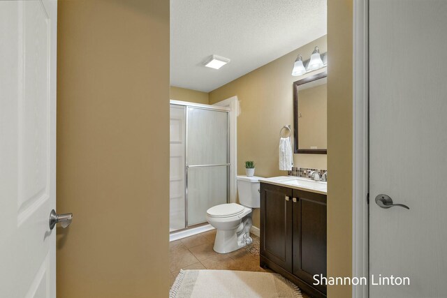 bathroom featuring tile patterned floors, a stall shower, toilet, and vanity