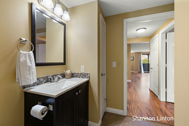bathroom with tile patterned flooring, baseboards, vanity, and tasteful backsplash