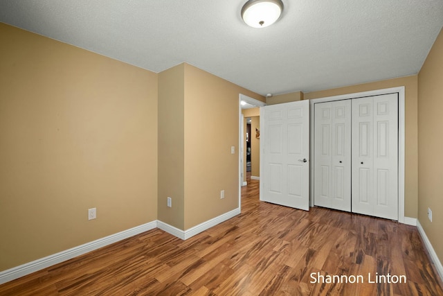 unfurnished bedroom with wood finished floors, a closet, and baseboards