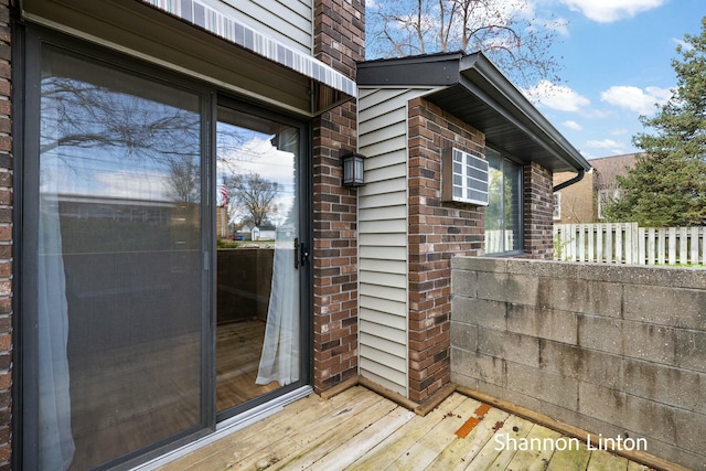 view of exterior entry with fence and brick siding