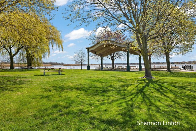 surrounding community with a water view and a lawn