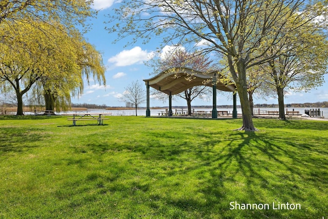 surrounding community with a water view and a lawn