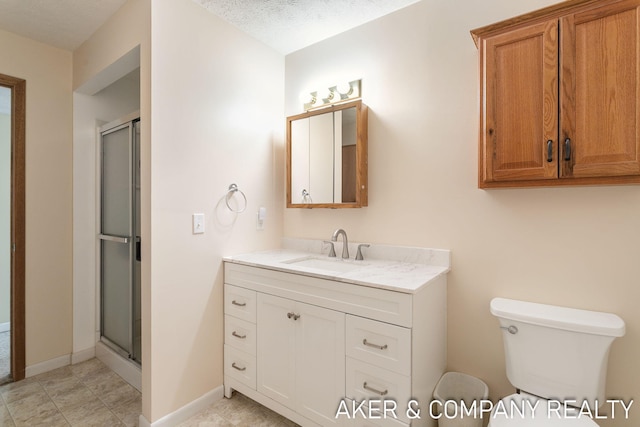 bathroom with vanity, baseboards, a stall shower, and toilet