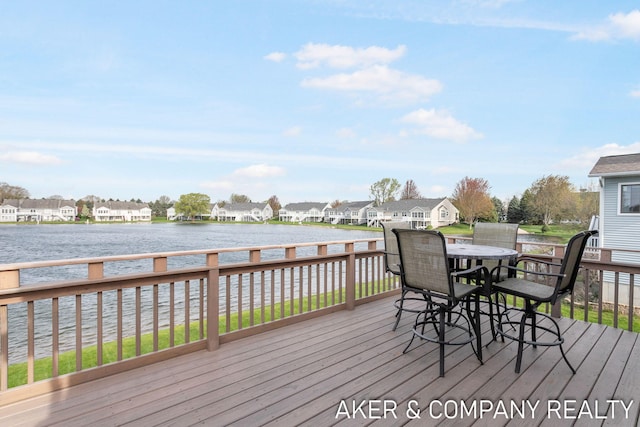 wooden terrace with a water view, a residential view, and outdoor dining area