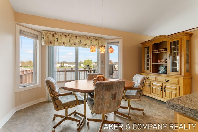 dining area featuring a water view, baseboards, and light tile patterned floors