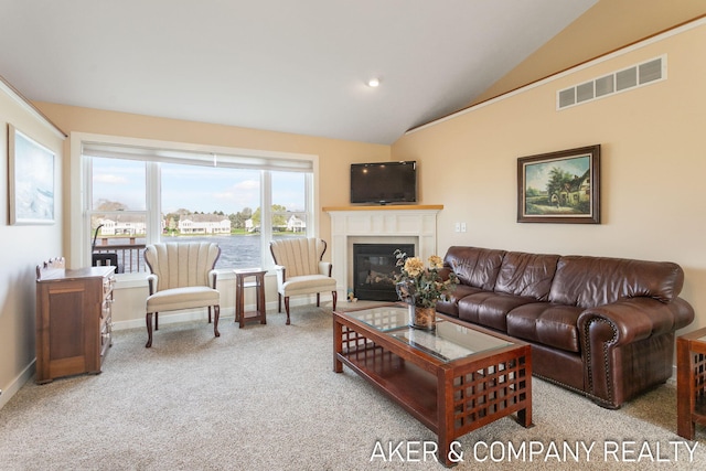 carpeted living room with baseboards, visible vents, a glass covered fireplace, and vaulted ceiling