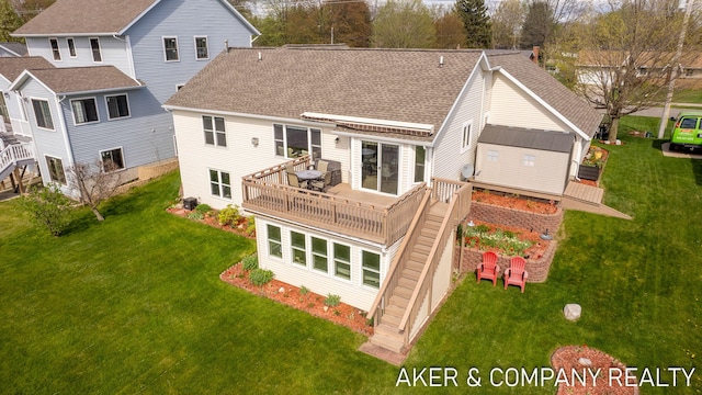 back of house featuring a lawn, a shingled roof, and a deck