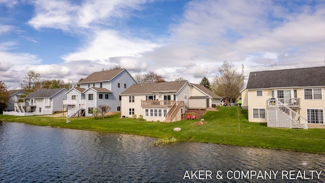 rear view of house featuring a lawn, a deck with water view, stairway, and a residential view