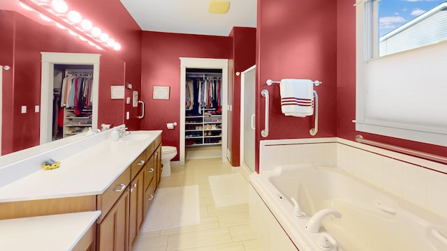 full bathroom featuring a walk in closet, a stall shower, a garden tub, and vanity