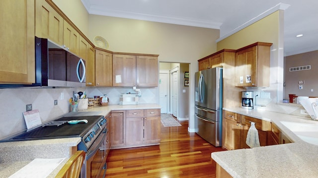 kitchen with appliances with stainless steel finishes, visible vents, tasteful backsplash, and crown molding