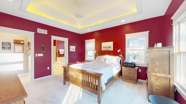 bedroom featuring connected bathroom, a raised ceiling, visible vents, and carpet floors