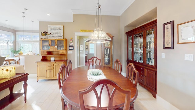 dining area featuring ornamental molding, a healthy amount of sunlight, light wood-style flooring, and an inviting chandelier