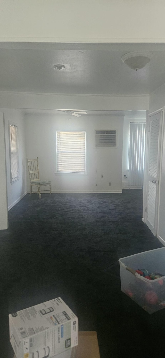 unfurnished room featuring dark colored carpet, baseboards, plenty of natural light, and a wall mounted AC