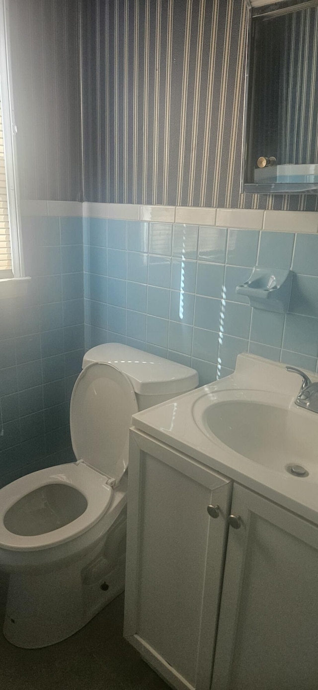 bathroom with vanity, tile walls, toilet, and wallpapered walls
