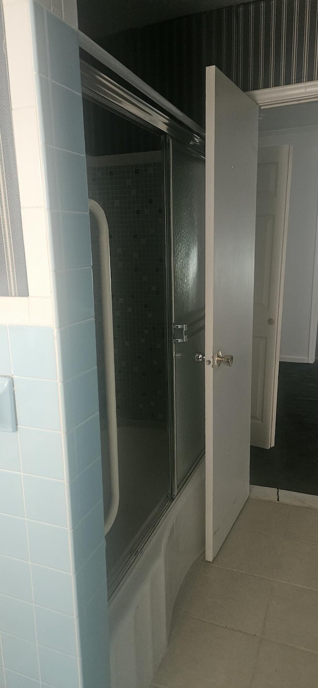 full bath with bath / shower combo with glass door and tile patterned flooring