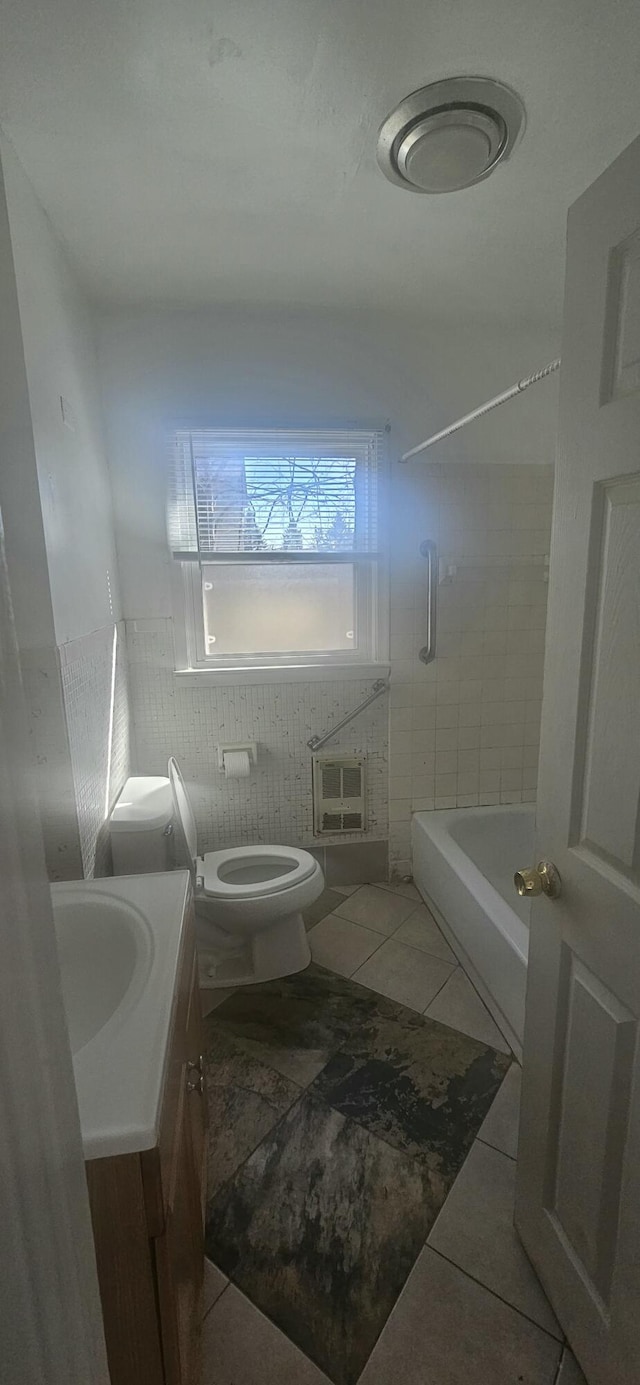bathroom featuring tile patterned flooring, vanity, toilet, heating unit, and bathing tub / shower combination