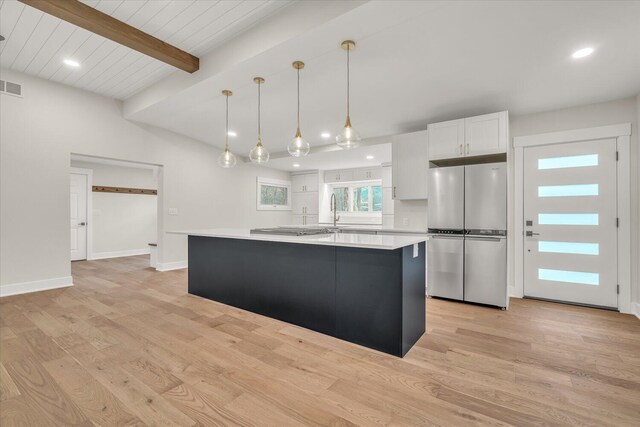 10985 E Cd Ave, Richland, MI 49083 - kitchen featuring appliances with stainless steel finishes, light countertops, light wood finished floors, white cabinetry, and a center island