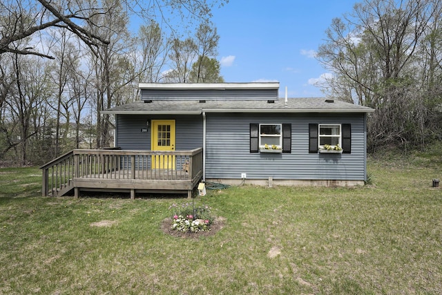 back of house featuring a shingled roof, a wooden deck, and a yard