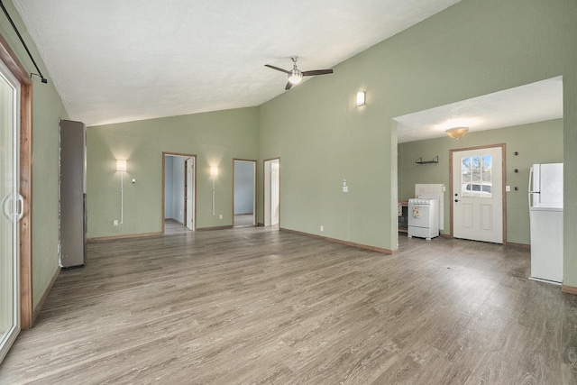 unfurnished living room featuring a ceiling fan, baseboards, light wood finished floors, and lofted ceiling