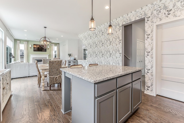 kitchen with wallpapered walls, dark wood finished floors, gray cabinets, and an inviting chandelier